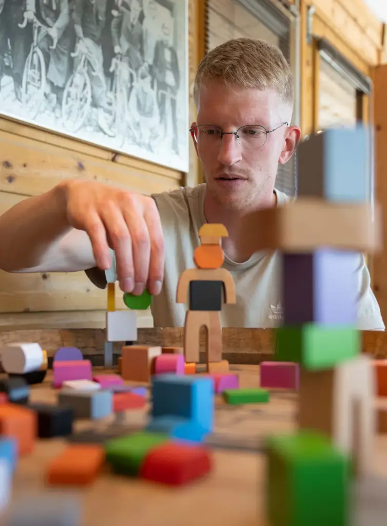 Jongeman bouwt geconcentreerd een toren van gekleurde houten blokken