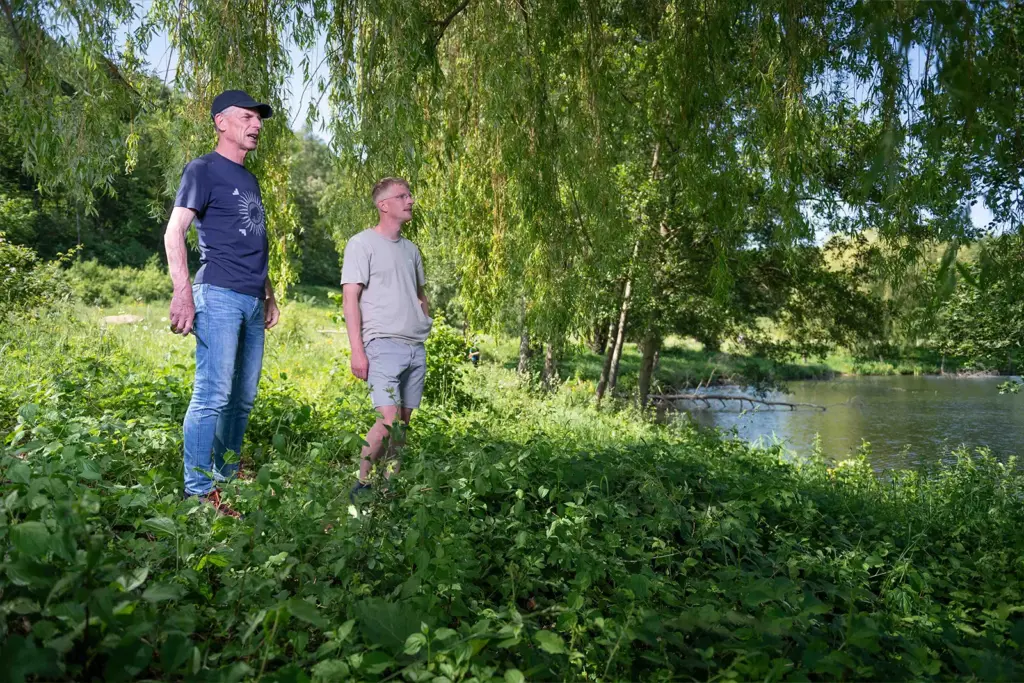 Peter Vos en een jongeman staan samen in het groen langs het water