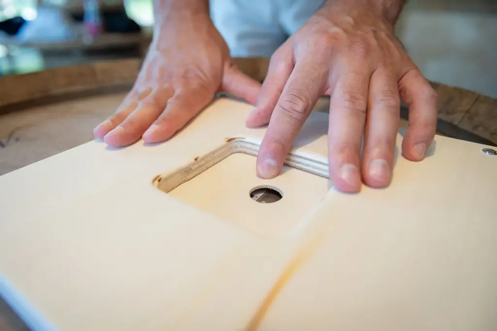 Handen schuiven een houten blokje in een uitsparing tijdens een opdracht van het Autisme Beleving Circuit